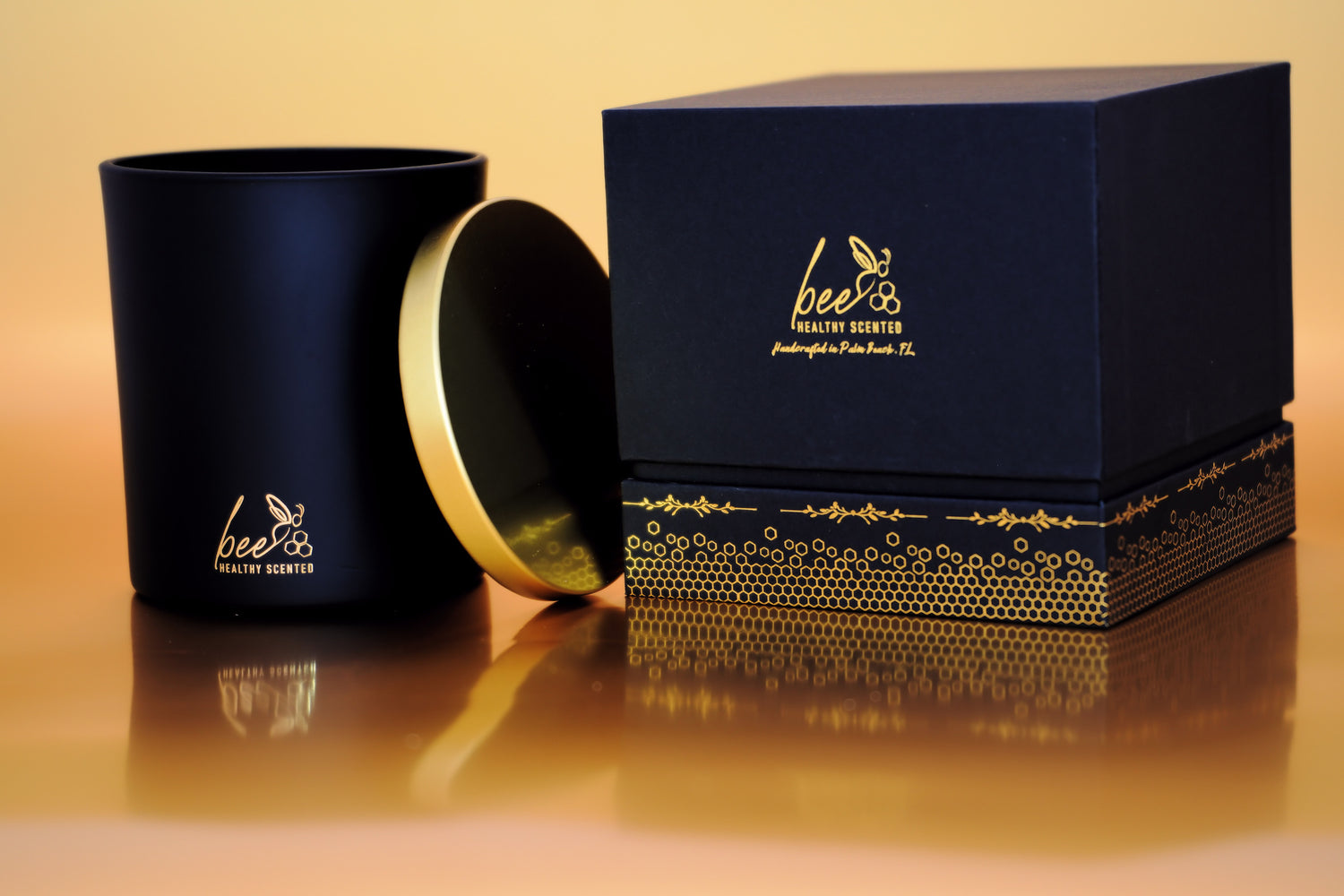 A black gift box and a Black luxury candle jar depicting the Bee Healthy Scented Logo and Honeycombs at the bottom  